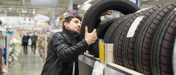 Un homme regarde le prix du pneu dans un magasin