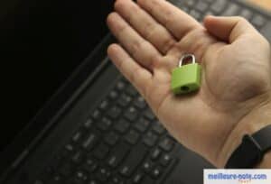 petite cadenas verte dans un main au dessus d'un clavier de laptop