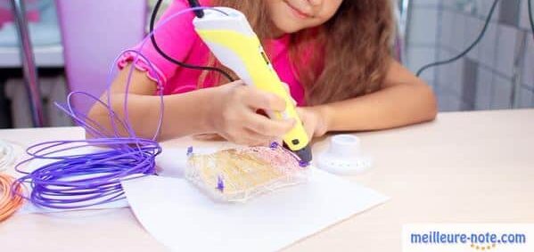 une petite fille écrit avec un stylo 3D