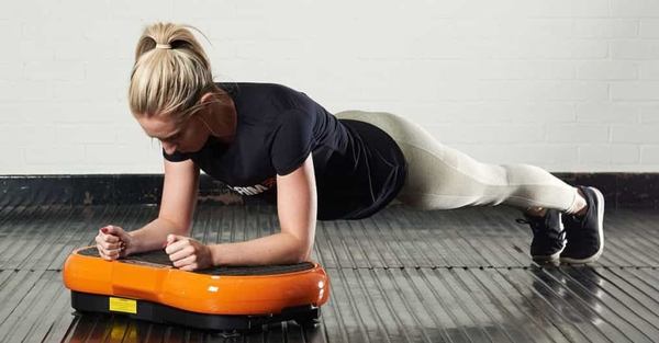 une femme fait un exercice sur une plateforme vibrante 