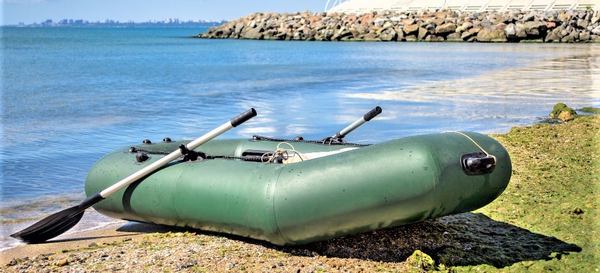 un bateau gonflable vert au bord de la mer