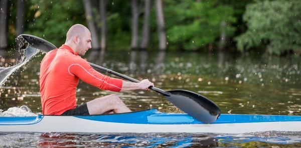 un homme porte son pagaie avec son kayak