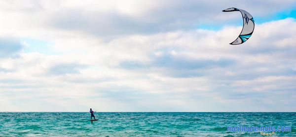 Une personne au milieu de la mer avec une aile de kitesurf