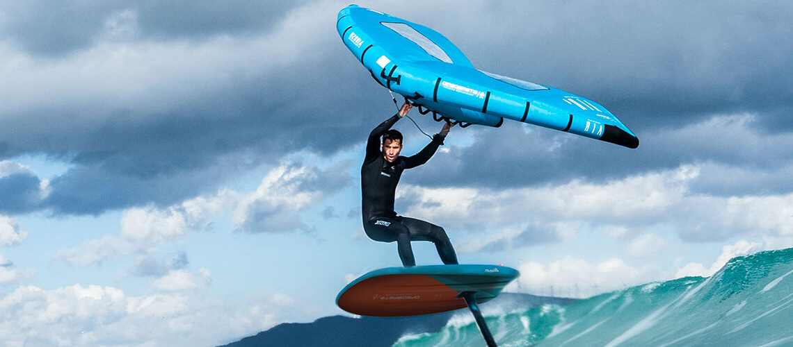 jeune homme qui fait du wingfoil sur une vague