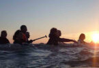 Groupe de personne faisant de la marche dans l'eau au coucher du soleil