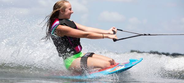 une femme sourit fait un sport de glisse 