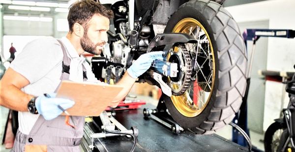 un homme vérifie une moto dans une garage