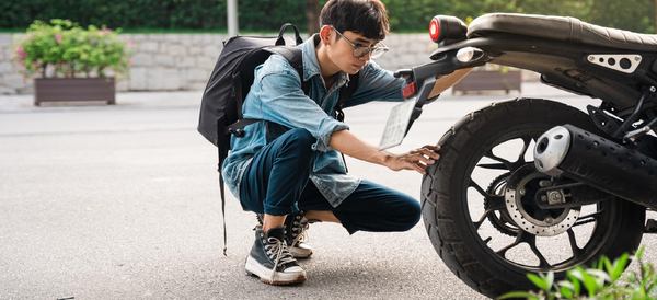 un garçon vérifie son pneu moto