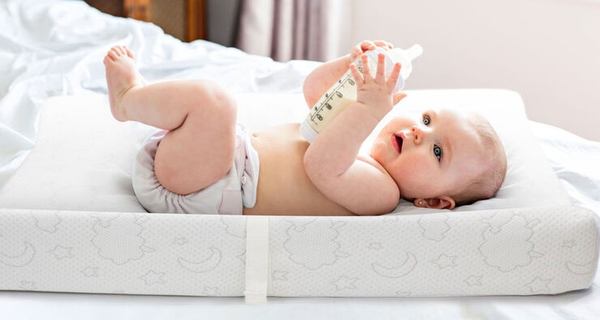 un petit bébé qui joue sur son lit à lange