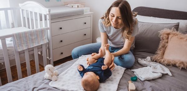 une maman occupe son bébé sur le lit à langer