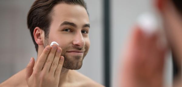 un homme met de la crème sur son visage