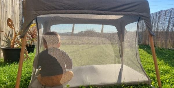 un bébé joue dans son lit parapluie