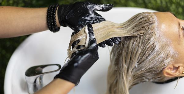 une coiffeuse fait la décoloration de cheveux